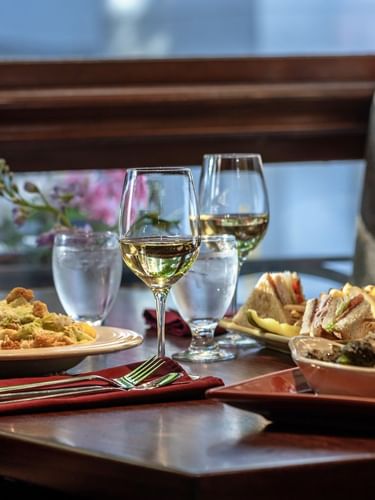 salad and club sandwiches by wine glasses on a table in Margaux Restaurant at Warwick Seattle