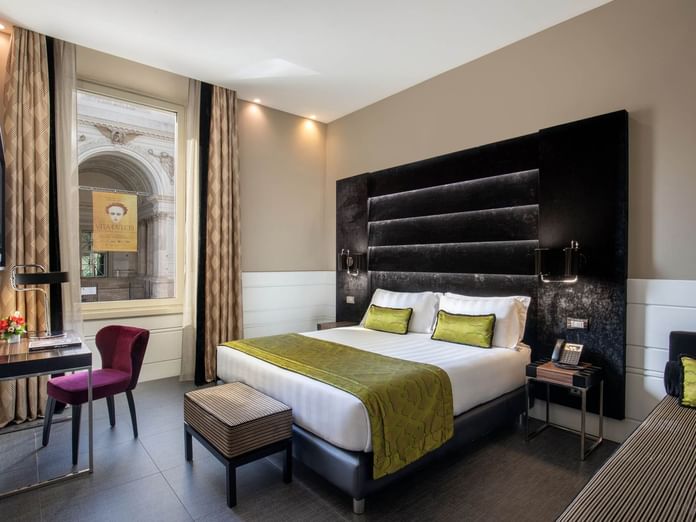 Work desk with bed by the window and wooden flooring in Deluxe Room at The Glam Hotel