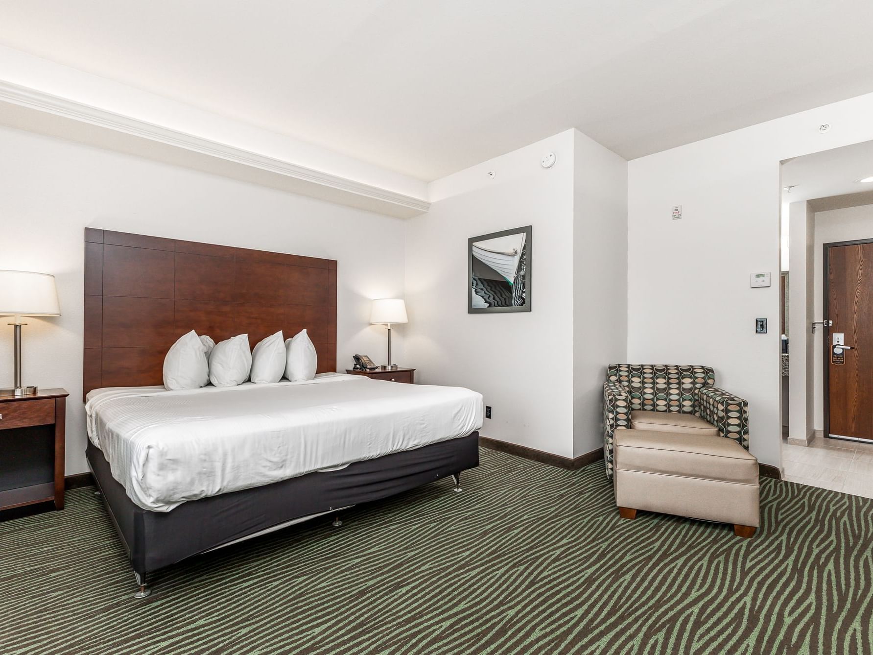 Nightstands and cozy lounge chair by the bed in King Handicap Resort View with carpeted floors at Off Shore Resort