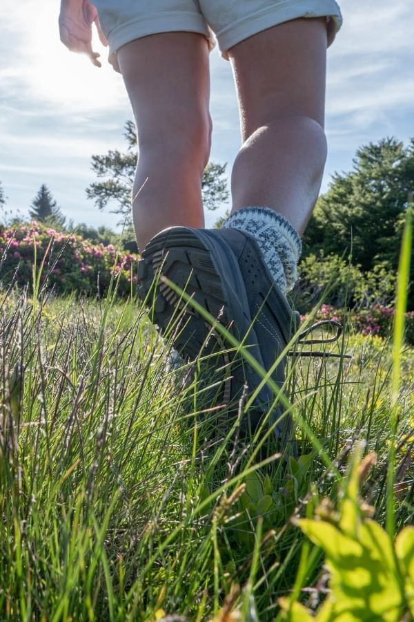 Person walking through tall grass, surrounded by green foliage at Avaneo Hotel, highlighting hotel sustainability