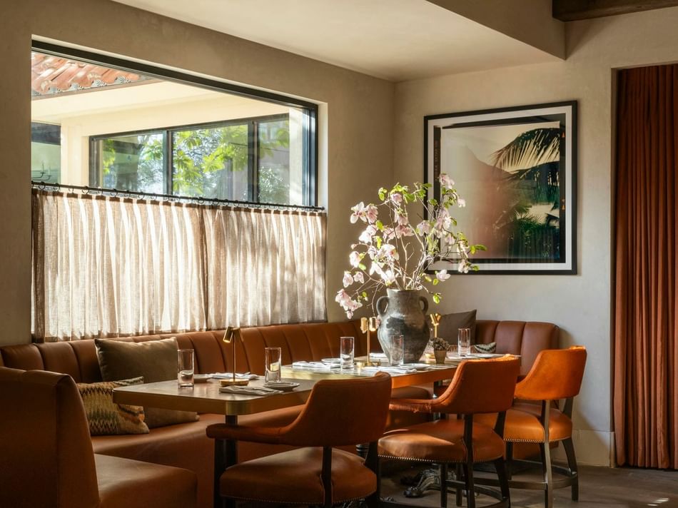 Stylish Bar Remi at Granduca Houston with leather seats, a floral vase, and soft natural light from large windows