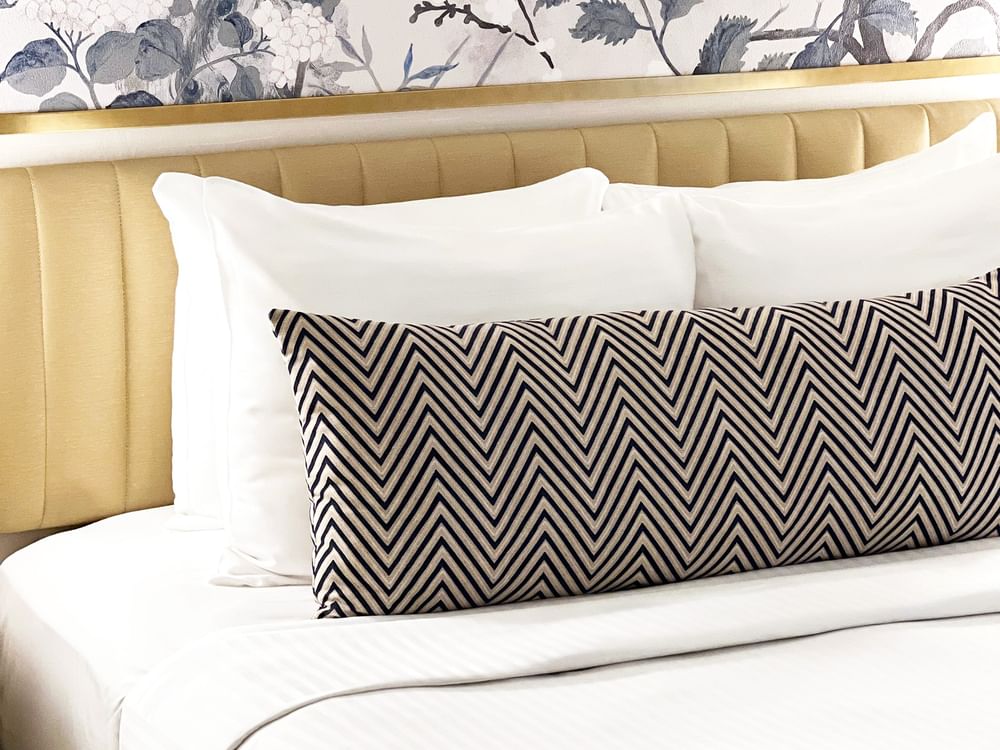 Close-up of a bed with a patterned pillow in Petite Classic at Warwick Allerton Chicago