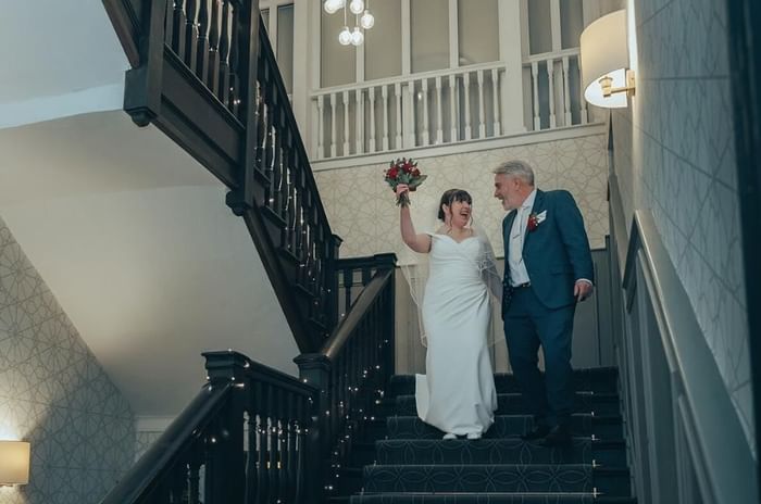 Bride and groom walking down ballroom stairs at Villiers Hotel Buckingham