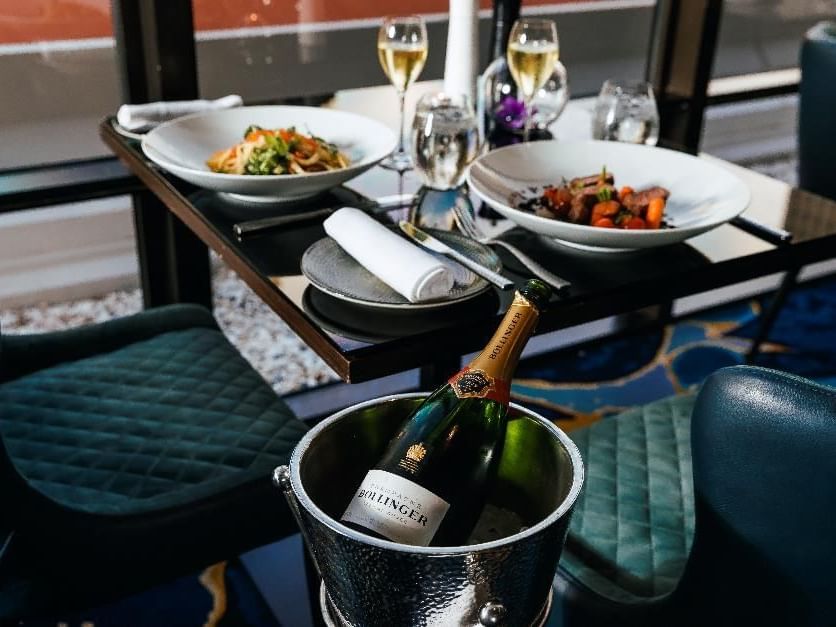 Restaurant Bistro Suzette Dinner setting with champagne in ice bucket and two pasta dishes at Sofitel Brisbane Central