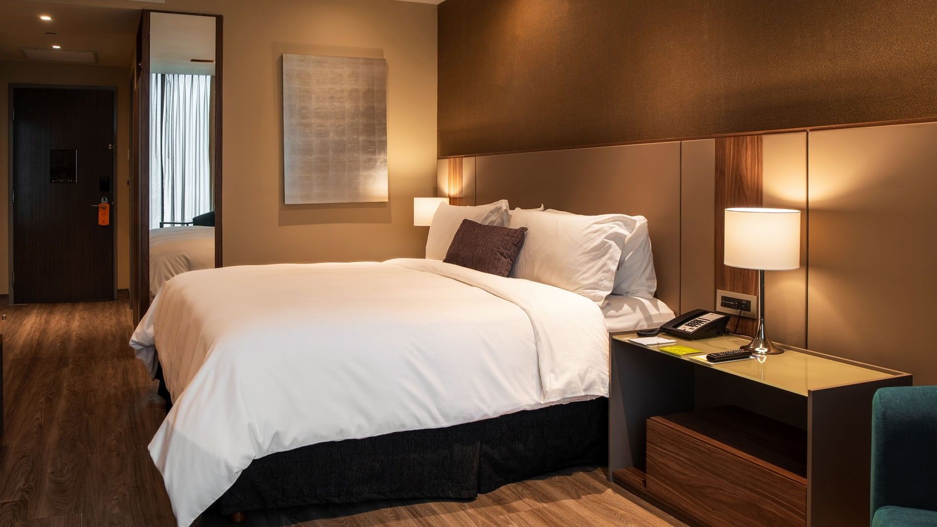 King Deluxe bedroom featuring white linens, bedside lamp, and silver artwork at Camino Real Fashion Drive, Monterrey