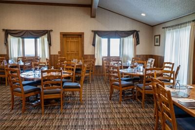 Spacious dining room at Blair Hotels featuring multiple round tables and classic wooden chairs