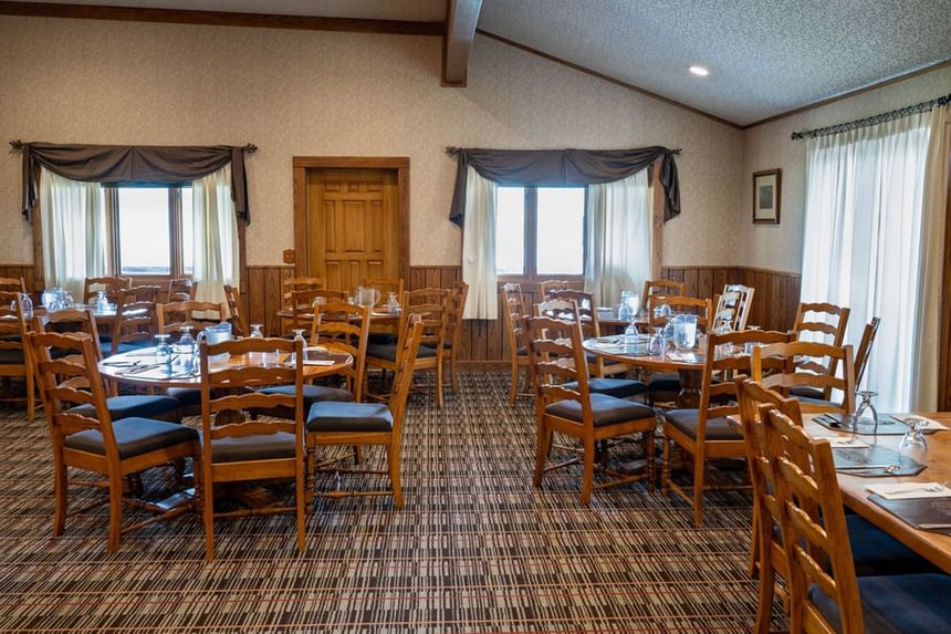 Spacious dining room at Blair Hotels featuring multiple round tables and classic wooden chairs