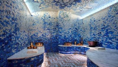 Spa space with blue mosaic tiles and marble seating, illuminated by soft lighting, in The Residences at Seafire