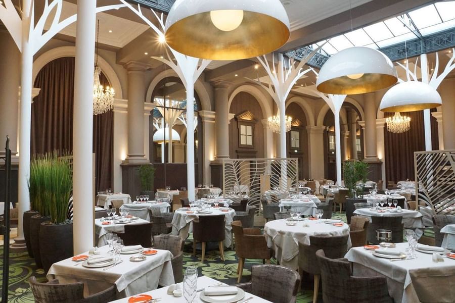 Restaurant La Verrière features dining tables and large dome lights with tree-like pillars at Le Grand Hôtel des Thermes