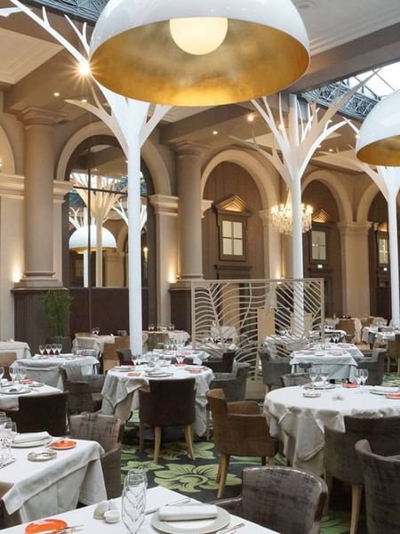 Indoor dining room with decorative tree structures in La Verrière restaurant at Le Grand Hôtel des Thermes