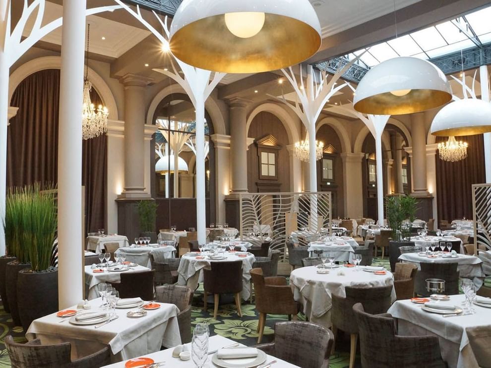 Indoor dining room with decorative tree structures in La Verrière restaurant at Le Grand Hôtel des Thermes