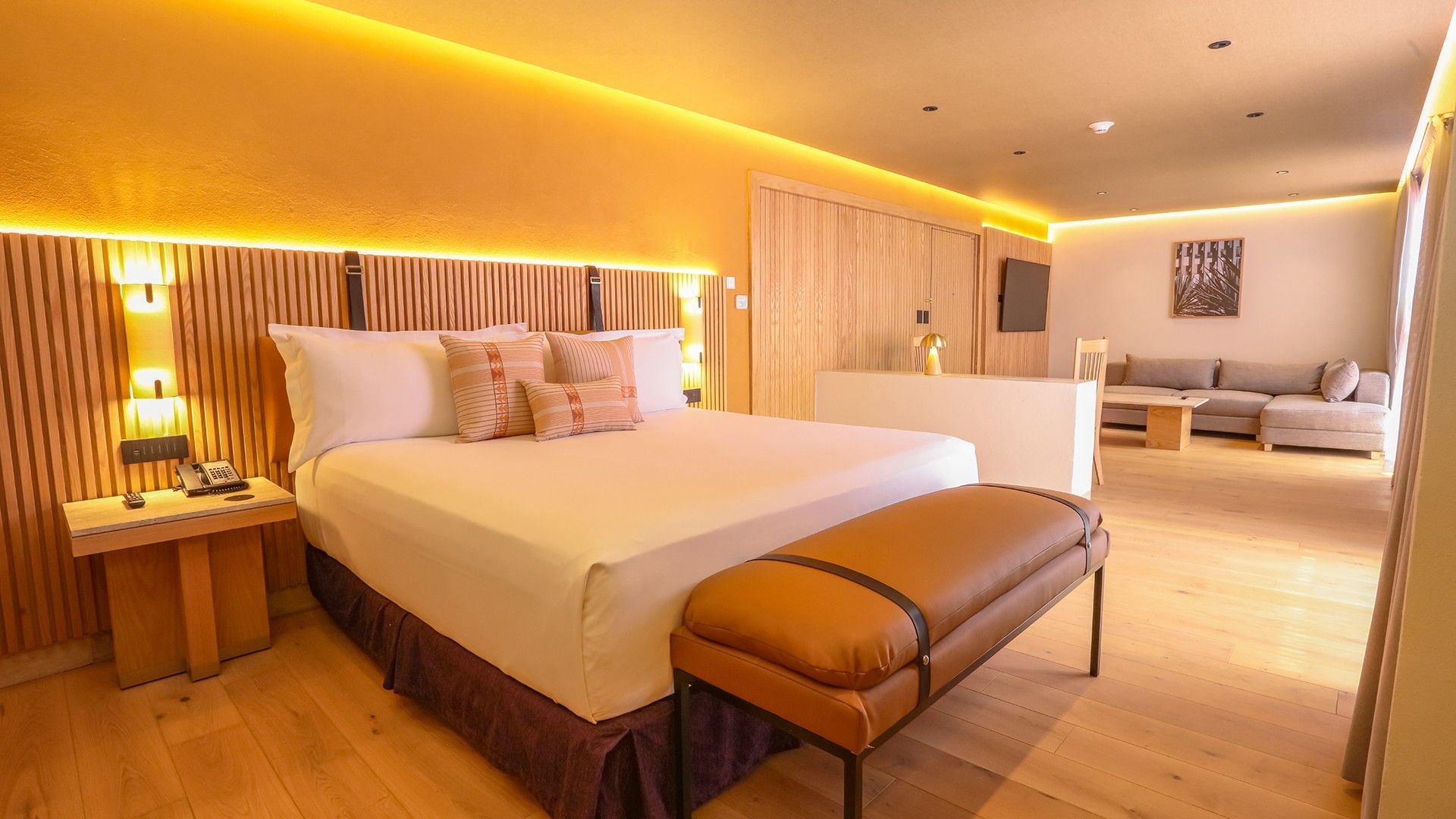 King Superior Junior Suite with a slatted wood headboard, leather bench, and orange walls at Camino Real Polanco Mexico