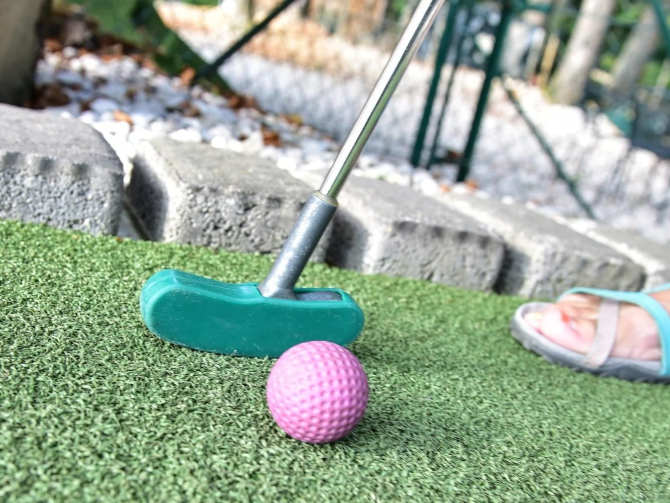 A person playing miniature golf with a pink ball at Wonder Mountain Fun Park near Anchorage by the Sea