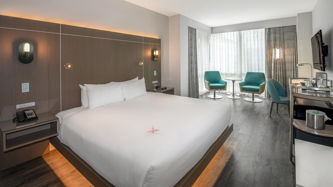 Hotel room with large bed, chairs, desk, and TV.