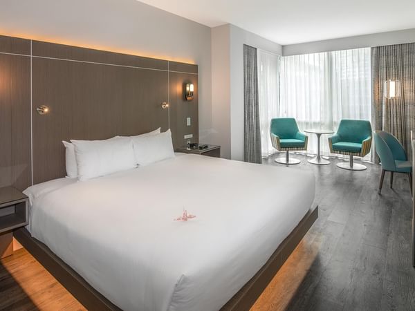 Spacious room with a King bed, two chairs, and TV.