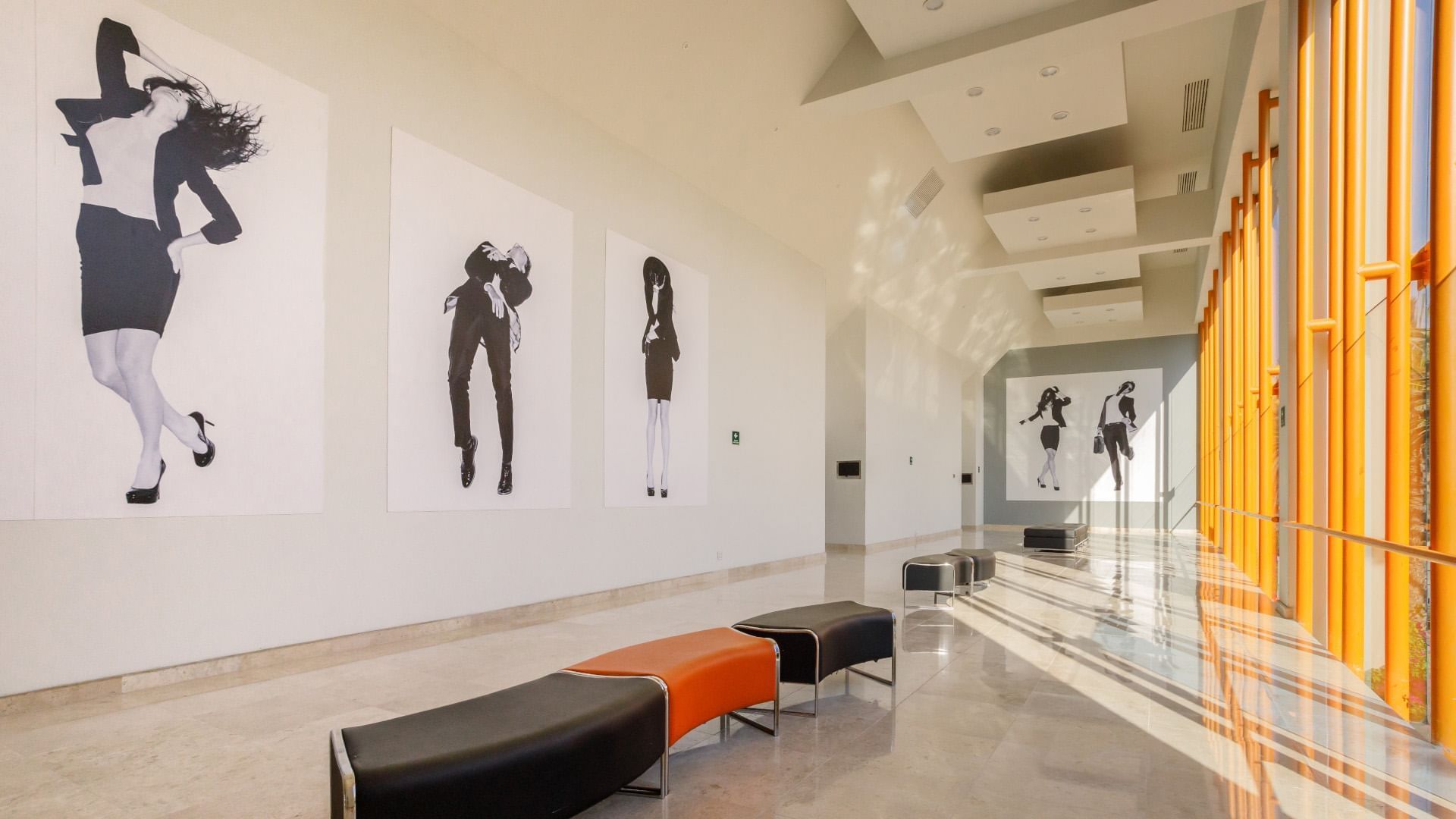 Foyer with black and white dance art and orange benches at the Real Inn Tijuana hotel