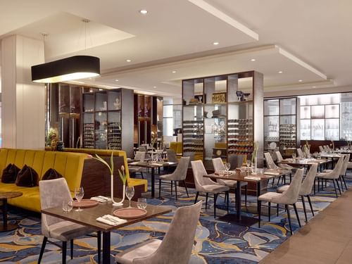 Dining area with yellow and grey chairs, and set tables in Restaurant Bistro Suzette at Sofitel Brisbane Central