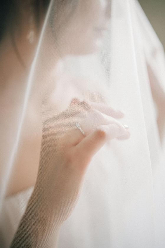 Bride’s hand at Paradox Bangkok Sukhumvit with diamond ring under sheer white veil, featuring a Bangkok hotel wedding