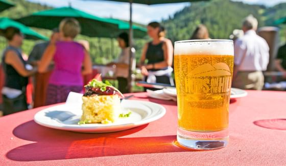 A plate of food and a beer is placed on a table near Stein Eriksen Residences
