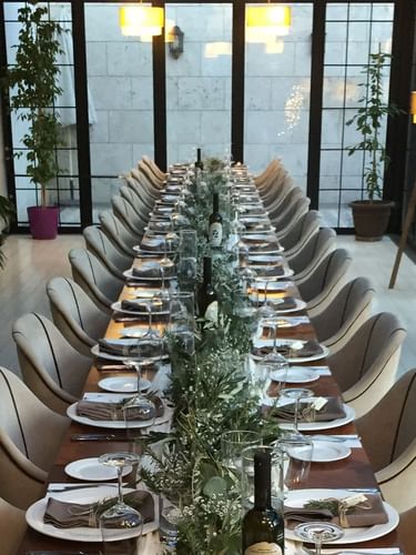Banquet table with wine by chairs surrounding a floral centerpiece in Maple Tree Restaurant at Warwick Ankara
