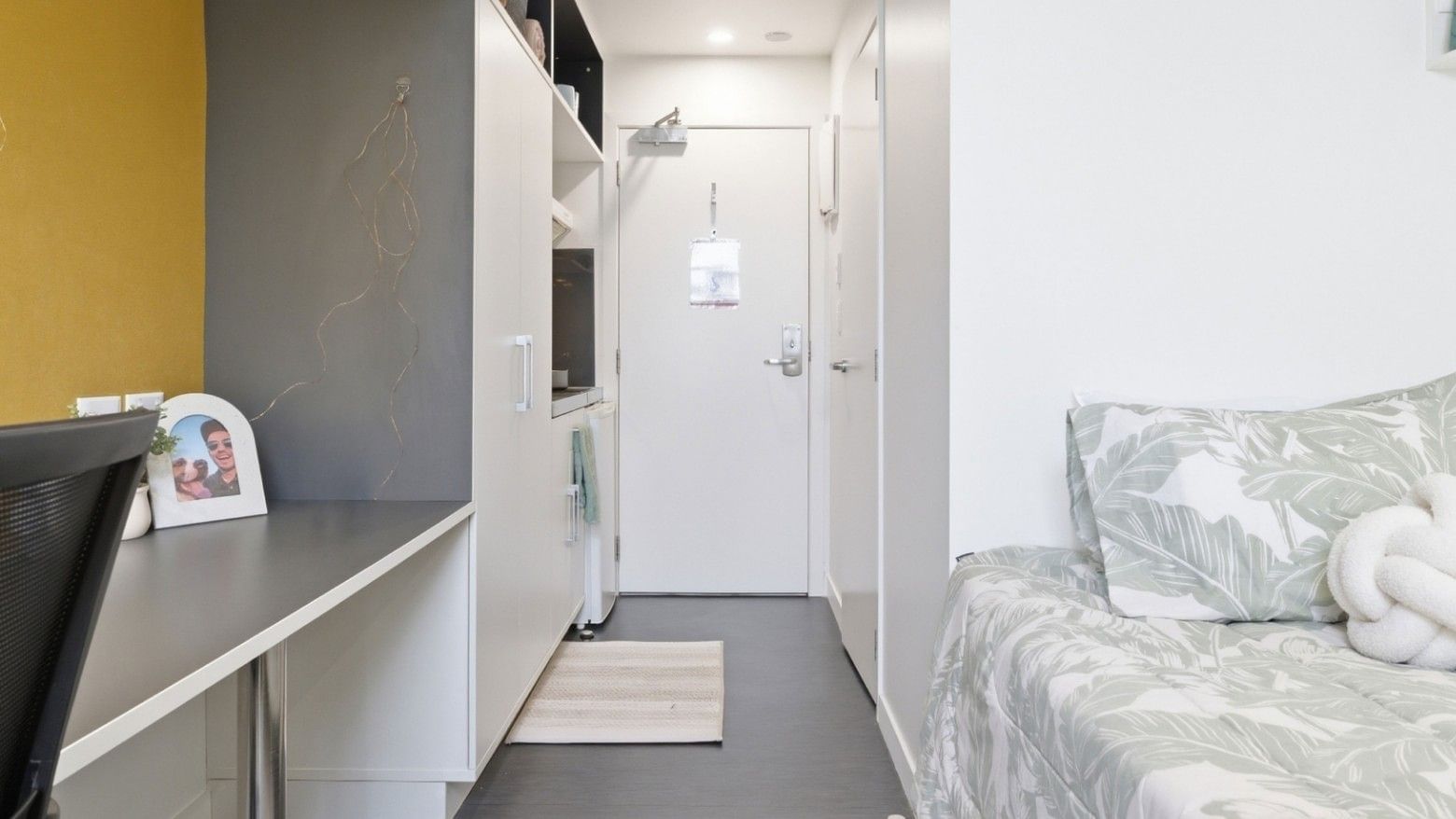 Clean and modern bedroom at UniLodge Auckland City with a bed, desk, and white door.