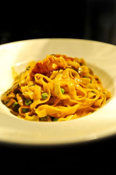 Tagliatelle pasta dish with green peas served in a white bowl at Farmington Inn and Suites