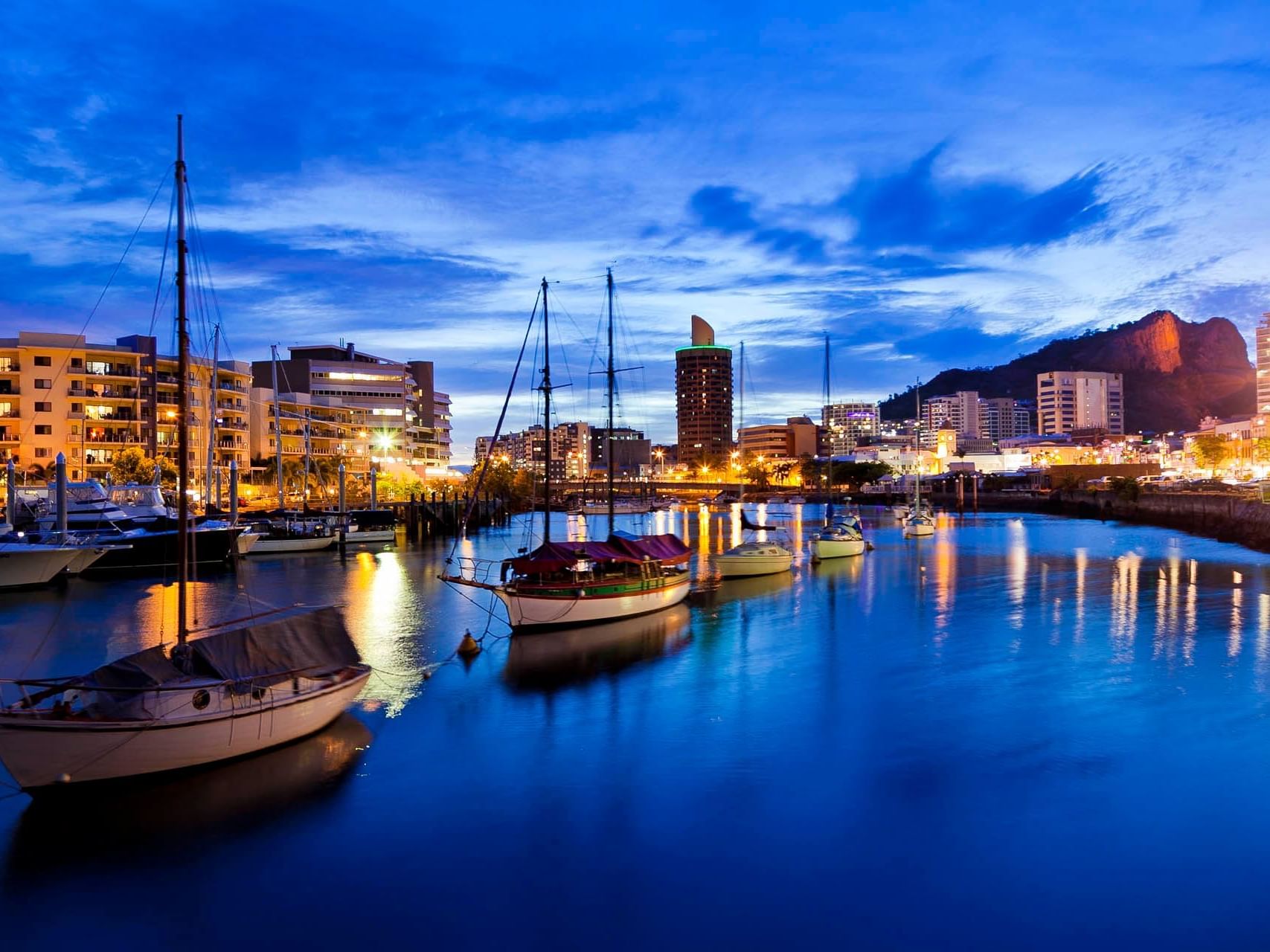 Boats stationed by the dock near Grand Chancellor Townsville at night