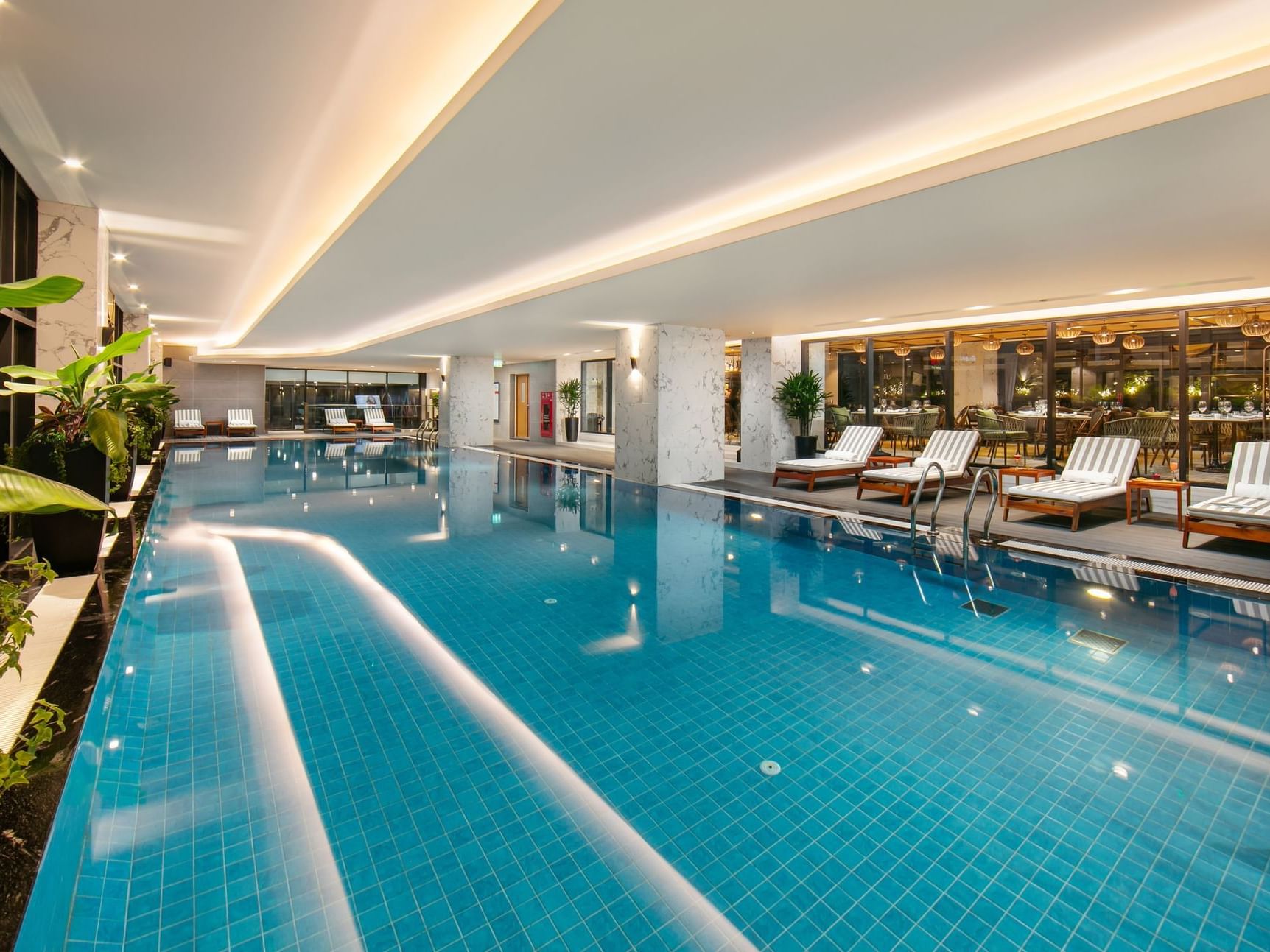 Indoor swimming area with pool loungers at Eastin Hotels