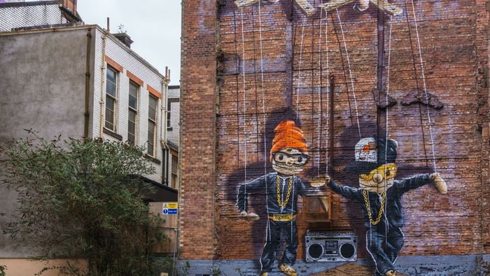 Street-art of 2 puppets on a break wall near Originals Hotels