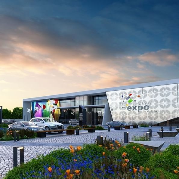 Dhahran Expo by parked cars under a soft sunset sky with vibrant banners near Warwick Al Khobar