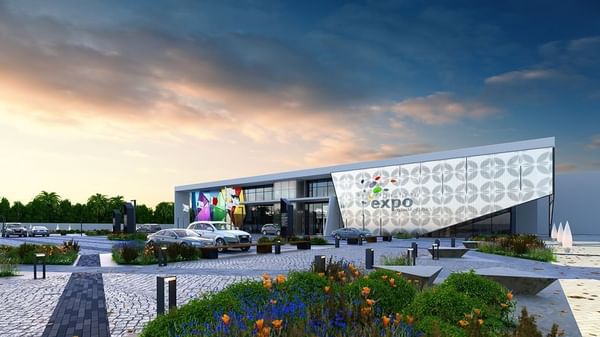 Exposition de Dhahran, avec des voitures garées sous un ciel aux couleurs douces du coucher de soleil et des bannières aux couleurs vives, près de Warwick Al Khobar