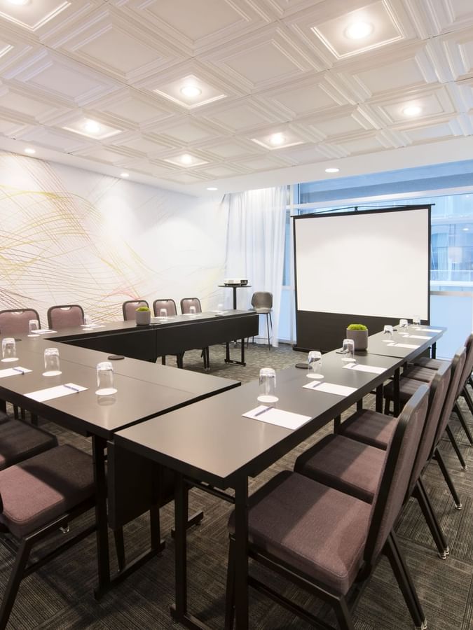 U-shaped table setup facing the projector screen in Salon Stanley at Warwick Le Crystal Montreal