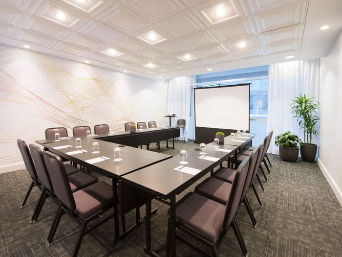 U-shaped table setup facing the projector screen in Salon Stanley at Warwick Le Crystal Montreal
