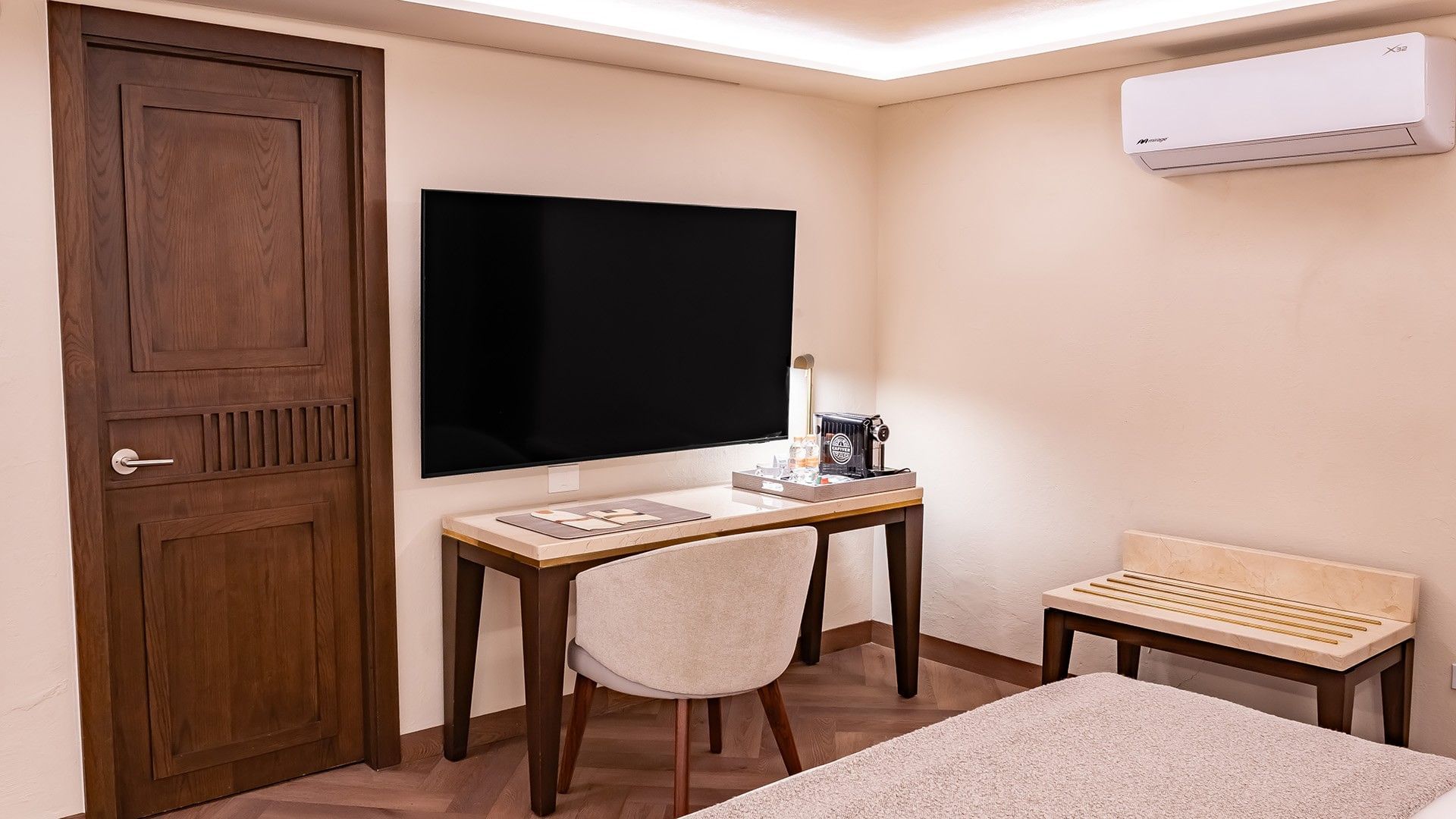 Desk area in Two Double New Class with a large TV, coffee maker, and a tan upholstered chair at Quinta Real Puebla