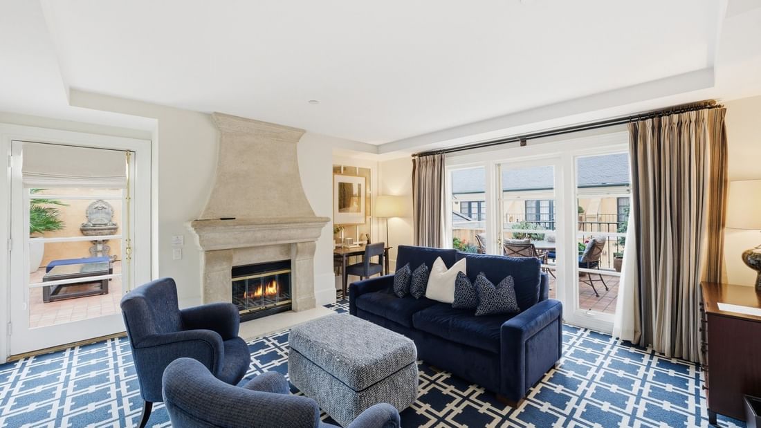Penthouse living room with fireplace, navy seating, and terrace access at el PRADO Hotel in Palo Alto.