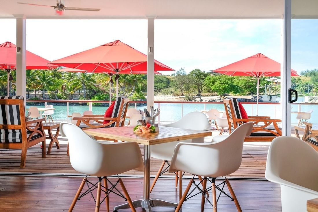 The Trader Cafe patio overlooking the water with umbrellas and modern chairs at Musket Cove Island Resort & Marina