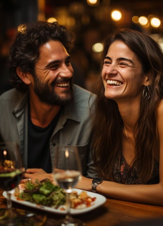 Couple laughing by a plate of salad under restaurant lighting near Paramount Hotel Seattle