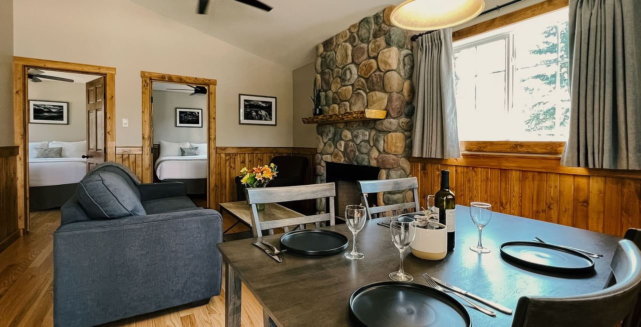 Cabin with two bedrooms, table, couch, and fireplace