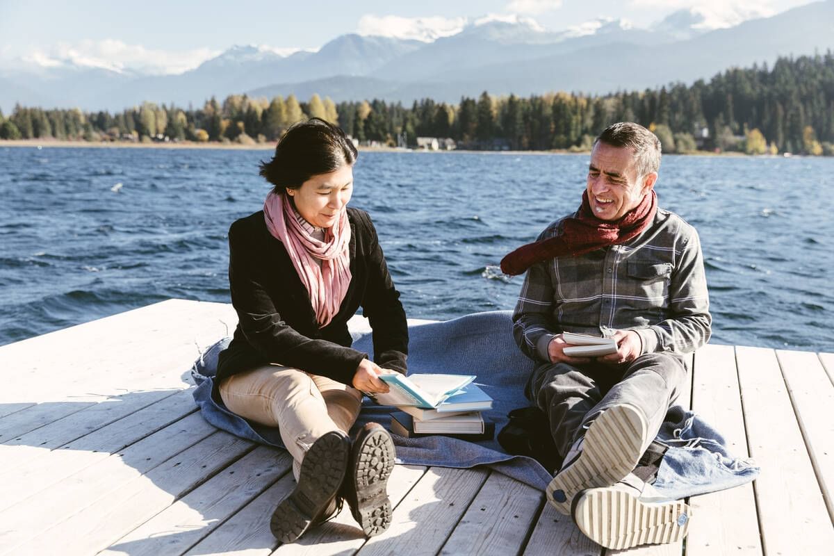 Adult couple relaxing on a wooden deck by the lake near Blackcomb Springs Suites