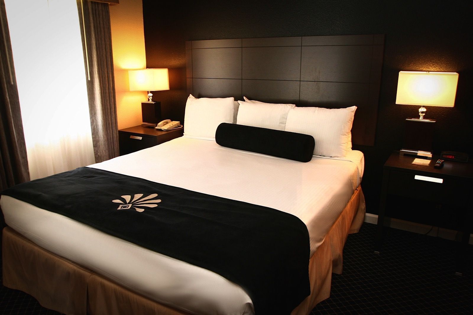 A hotel room with a large bed, two nightstands, and a window.