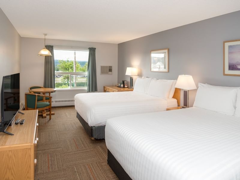 Two beds, a TV, a small table, a window, and two framed pictures on the wall.