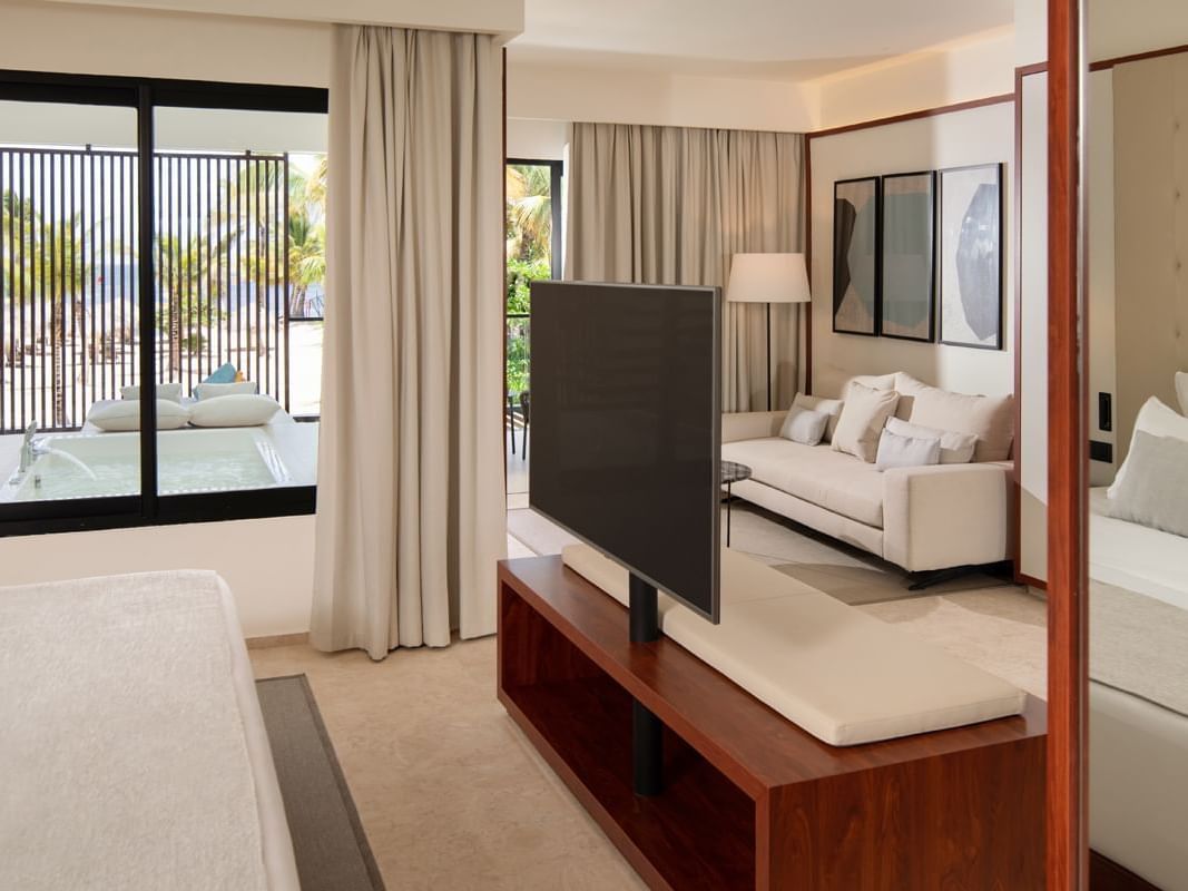 Bed and TV with separate living area in Luna Suite at Live Aqua Resorts