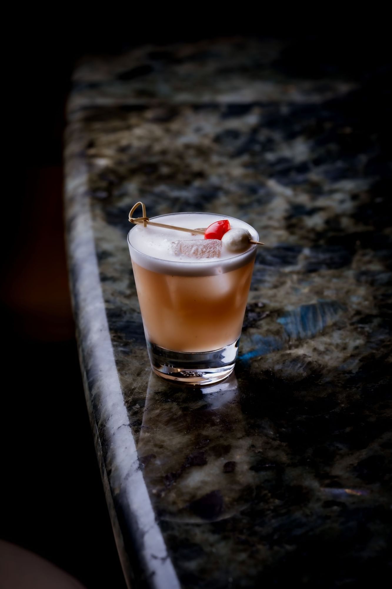 Cocktail with fruit garnish on a marble surface at The May Fair Bar.