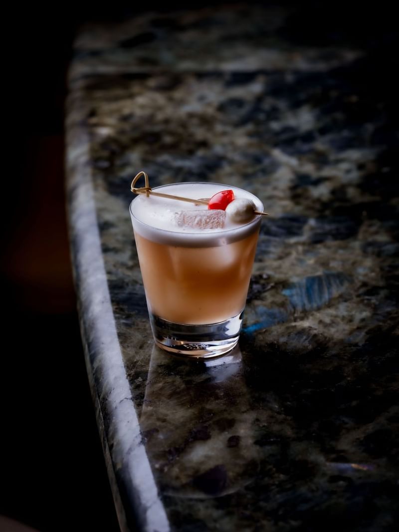 Cocktail with fruit garnish on a marble surface at The May Fair Bar.