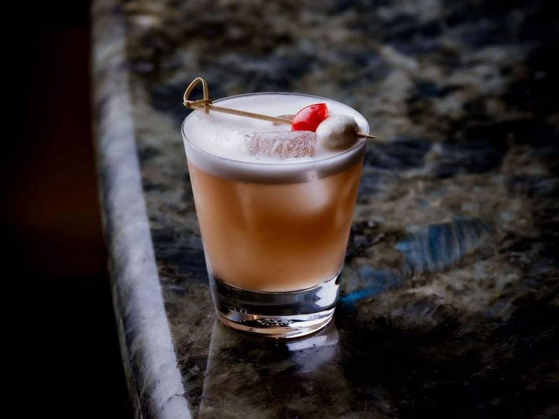 Cocktail with fruit garnish on a marble surface at The May Fair Bar.