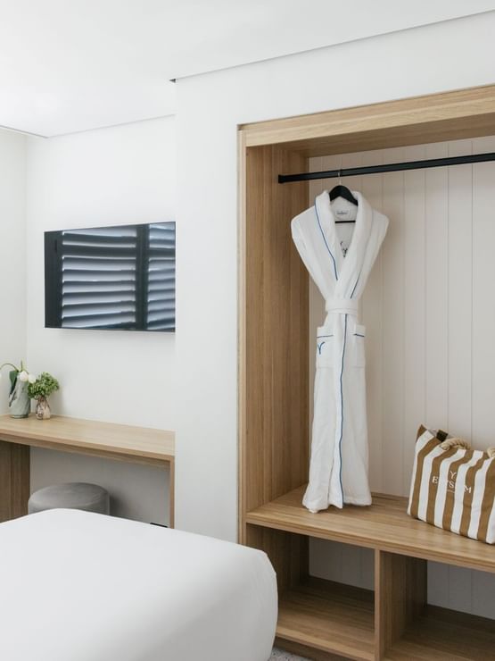 Coastal Two Bedroom Suite at Elysium Manly with white beds by a wooden desk, surrounding a TV on the wall and a robe