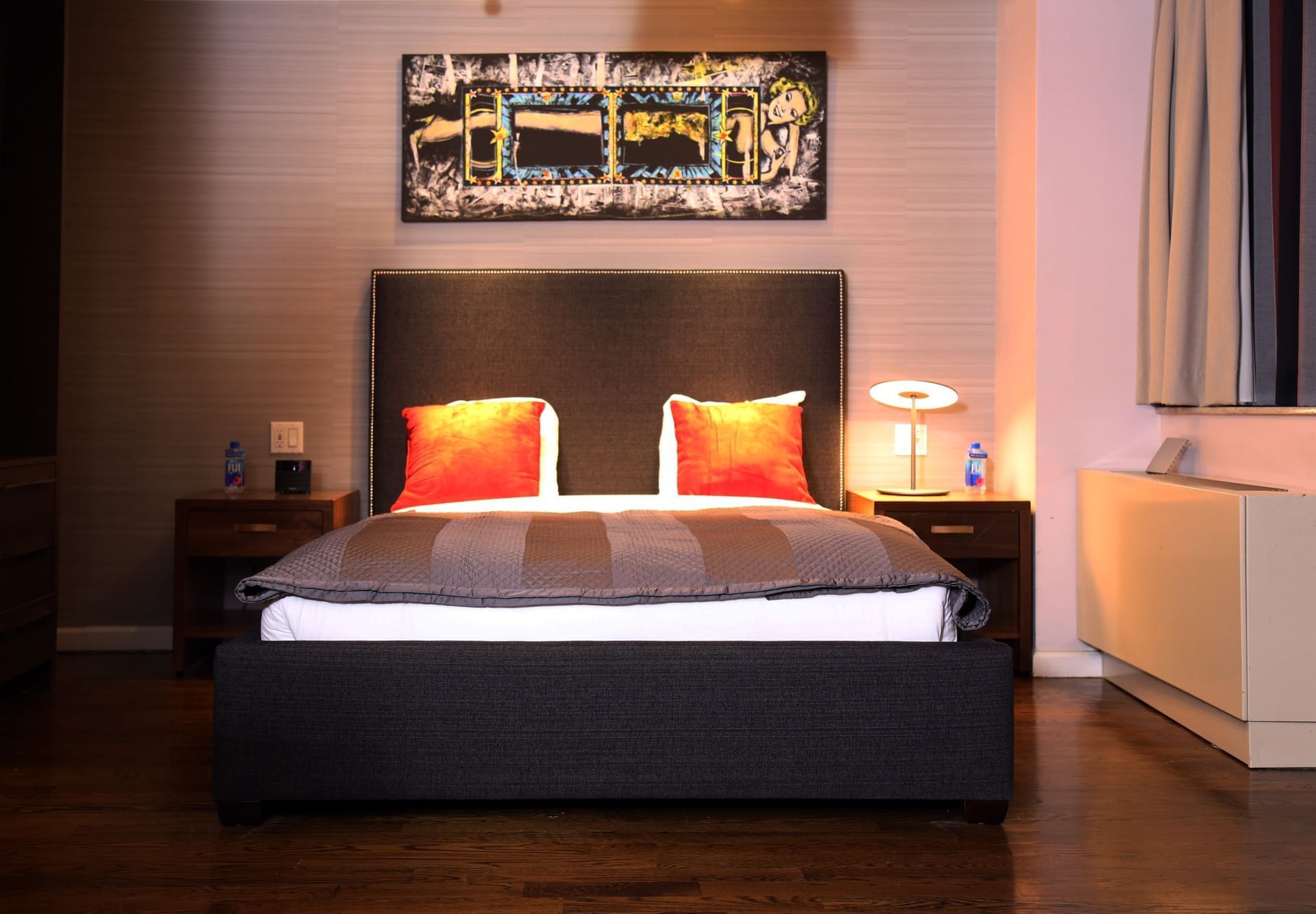 A wide view of a hotel room with a large bed, two nightstands, and artwork above the bed.
