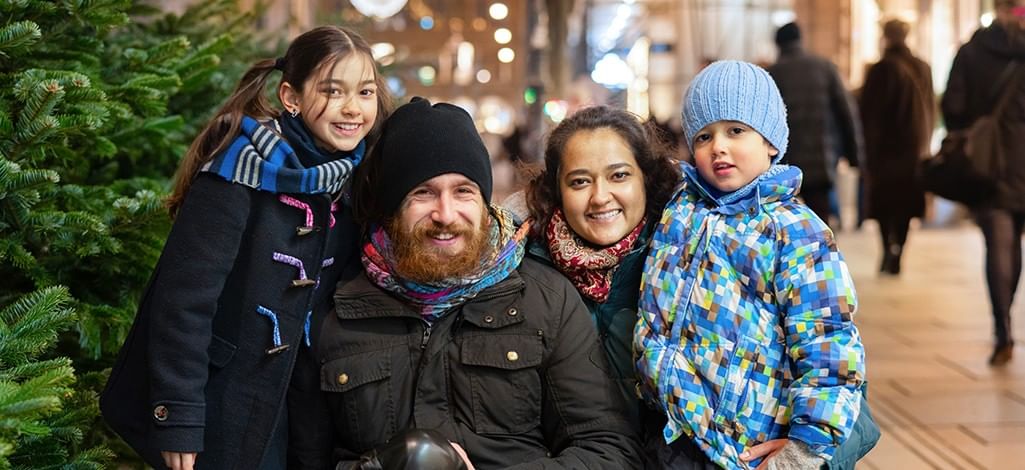 Family taking a photo by a decorated Christmas tree while out shopping