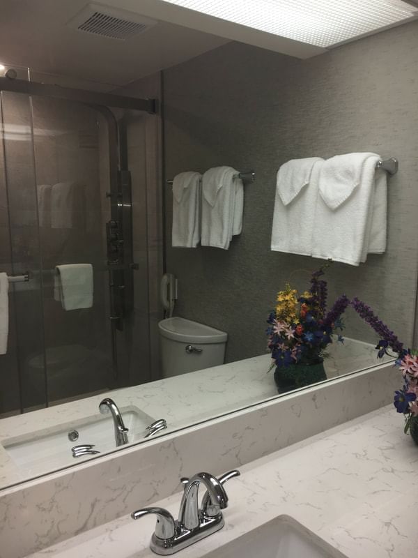 A bathroom with a sink & mirror at Cartier Place Suite Hotel