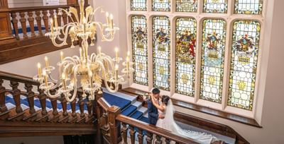Newlyweds posing by a stairway at Easthampstead Park Hotel